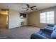 Comfortable living area with a plush sofa, a ceiling fan, and a TV for cozy entertainment at 11832 W Electra Ln, Sun City, AZ 85373