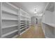 Walk-in closet featuring custom shelving and drawers, wood-look floors, and modern lighting at 12222 N 74Th St, Scottsdale, AZ 85260