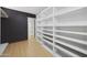 Walk-in closet featuring custom shelving and drawers, wood-look floors, and a dark accent wall at 12222 N 74Th St, Scottsdale, AZ 85260