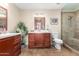 Well-lit bathroom featuring cherry-wood vanity, tile floors, decorative accents, and a glass-enclosed tiled shower at 15014 N 48Th Pl, Scottsdale, AZ 85254