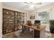 Well-lit home office featuring a large wooden desk, bookshelves, and a comfortable leather chair near a window at 15014 N 48Th Pl, Scottsdale, AZ 85254