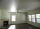 Bright living room with a ceiling fan, fireplace, and large windows overlooking the backyard at 18548 W Sunbelt Dr, Surprise, AZ 85374