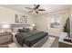 Cozy bedroom featuring a ceiling fan, stylish gray furnishings, and bright natural light from the window at 3450 W Kaler Dr, Phoenix, AZ 85051