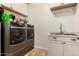 This laundry room has a pair of silver washing machines, a sink, and cabinets at 5235 S Dante --, Mesa, AZ 85212