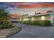 Ranch home with desert landscaping, a covered walkway and an ample driveway as the sun sets in the distance at 7030 E Orange Blossom Ln, Paradise Valley, AZ 85253