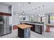 Open-concept kitchen with stainless steel appliances, a butcher block island and an eat-in breakfast bar with granite countertops at 7911 E Posada Ave, Mesa, AZ 85212