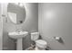 Bathroom featuring a pedestal sink, round mirror, and toilet at 8468 W Lewis Ave, Phoenix, AZ 85037