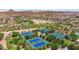 Aerial view showcasing multiple tennis courts with lush green landscaping, and views of the surrounding neighborhood at 8516 W Clemente Way, Florence, AZ 85132