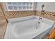 Soaking tub featuring tiled surround, a window for natural light, and a shower head at 8820 W Glenn Dr, Glendale, AZ 85305