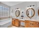 Bright bathroom featuring double sinks, framed mirrors, a tub, and vanity at 8820 W Glenn Dr, Glendale, AZ 85305