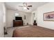 This bedroom boasts neutral paint, soft carpet, multiple windows, a ceiling fan, and a TV at 11959 W Pierce St, Avondale, AZ 85323