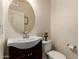 Cozy powder room featuring a pedestal sink, round mirror, and a toilet at 11959 W Pierce St, Avondale, AZ 85323