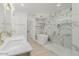 Bright bathroom featuring marble-style tile, double sinks, a bathtub and shower with glass doors at 126 E Northern Ave, Phoenix, AZ 85020