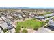 An aerial view of a community with a large green space, desert landscaping, and stunning mountain views in the distance at 1384 S 222Nd Ln, Buckeye, AZ 85326