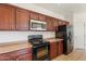Functional kitchen featuring dark wood cabinets and standard appliances at 1441 N 80Th Ln, Phoenix, AZ 85043