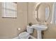 Well-lit half bathroom featuring a pedestal sink, round mirror, and contemporary fixtures, perfect for guests at 15046 W Post Dr, Surprise, AZ 85374