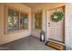 Inviting front porch with a charming welcome mat, a decorative lantern, a wreath and sunlit windows at 15046 W Post Dr, Surprise, AZ 85374