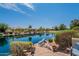 Landscaped backyard with a scenic view of the lake, lush plants, and luxurious seating at 20119 N Laguna Way, Maricopa, AZ 85138
