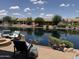 Scenic waterfront backyard featuring brick patio, lush landscaping and comfortable outdoor seating at 20119 N Laguna Way, Maricopa, AZ 85138