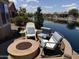 Beautiful waterfront backyard featuring a fire pit, comfortable seating and lush landscaping at 20119 N Laguna Way, Maricopa, AZ 85138