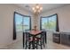 Dining area featuring a black wood table, seating for four, a chandelier, and window views at 20119 N Laguna Way, Maricopa, AZ 85138