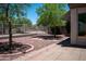 A picturesque backyard with a brick-paved patio area, trees, and decorative rock landscaping at 20443 N 39Th Dr, Glendale, AZ 85308