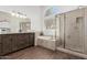 Elegant bathroom featuring a soaking tub, a glass enclosed shower, a double sink vanity and wood-look tile floors at 2137 E New Bedford Dr, Gilbert, AZ 85234