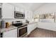 Updated kitchen with stainless steel appliances, granite countertops, white cabinets, and wood-look tile flooring at 2137 E New Bedford Dr, Gilbert, AZ 85234