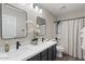 Elegant bathroom featuring double sinks, black fixtures, modern lighting, and shower with patterned curtain at 3123 E Buena Vista Dr, Chandler, AZ 85249