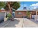 Tree-lined backyard with covered patio and access to the house, under a partly cloudy sky at 4026 W Berridge W Ln, Phoenix, AZ 85019