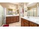 Bright bathroom featuring double sinks, wood cabinets, and a glass-enclosed shower at 42709 W King Fisher Dr, Maricopa, AZ 85138