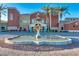 Large fountain at community center with decorative stonework and colorful building facade with palm trees at 42709 W King Fisher Dr, Maricopa, AZ 85138