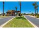 Gated community entrance with guard house, palm trees, and well-maintained landscaping on a sunny day at 42709 W King Fisher Dr, Maricopa, AZ 85138