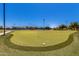 Community putting green showcasing manicured lawns, flag markers, and blue skies, promising a relaxing amenity at 42709 W King Fisher Dr, Maricopa, AZ 85138