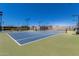 Well-maintained tennis court with blue and green surface, netting, and surrounding community amenities under blue skies at 42709 W King Fisher Dr, Maricopa, AZ 85138