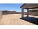 Unfinished backyard featuring a covered patio, surrounded by a tall block wall at 5669 S 253Rd Ave, Buckeye, AZ 85326