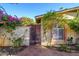 Charming exterior view with a gated entrance, stucco walls, flowering plants, and brick-framed windows at 6255 E Crocus Dr, Scottsdale, AZ 85254