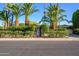 Charming home exterior featuring mature palm trees, lush greenery, and a unique wood gate entrance at 6255 E Crocus Dr, Scottsdale, AZ 85254