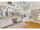 Bright bathroom with tub, walk in shower, dual sink vanity, ceiling fan, and shuttered window at 7525 E Gainey Ranch Rd # 164, Scottsdale, AZ 85258