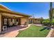 Inviting backyard with covered patio, chairs, synthetic grass, and mature desert landscaping at 8355 E Vía De Los Libros --, Scottsdale, AZ 85258