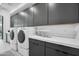 Modern laundry room with front load washer and dryer, quartz countertops, and sleek gray cabinets at 12746 E Casitas Del Rio E Dr, Scottsdale, AZ 85255