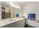Bathroom with double sink vanity and a large mirror, complemented by stylish fixtures and green tile in the shower at 1351 E Ellis Cir, Mesa, AZ 85203