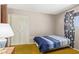 Cozy bedroom featuring a blue-striped bedspread, a white closet, and bright curtains by the window at 1351 E Ellis Cir, Mesa, AZ 85203
