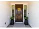 Inviting front entrance with a stylish door, decorative wreath, potted plants, and a striped welcome mat at 1360 E Avenida Kino --, Casa Grande, AZ 85122