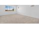 Bright, carpeted bedroom featuring neutral walls, a large window, and minimalist design at 17051 W West Wind Dr, Surprise, AZ 85387