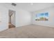 Empty bedroom with plush carpeting, an open door to the bathroom, and a bright window at 17051 W West Wind Dr, Surprise, AZ 85387
