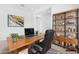 Bright home office features a wooden desk, black chair, and stylish shelving with decorations at 17051 W West Wind Dr, Surprise, AZ 85387