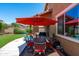 Inviting back patio with dining set under a red umbrella, overlooking a spacious, green backyard at 2120 N Heritage St, Buckeye, AZ 85396