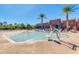 Zero entry community pool with a ramp, palm trees, lounge chairs and blue umbrellas at 2120 N Heritage St, Buckeye, AZ 85396