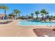 Large community pool surrounded by palm trees, lounge chairs and blue umbrellas at 2120 N Heritage St, Buckeye, AZ 85396